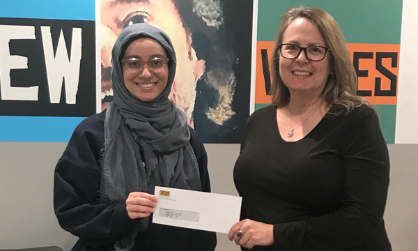 Israa (L) is presented with her scholarship cheque by her union rep Shauna